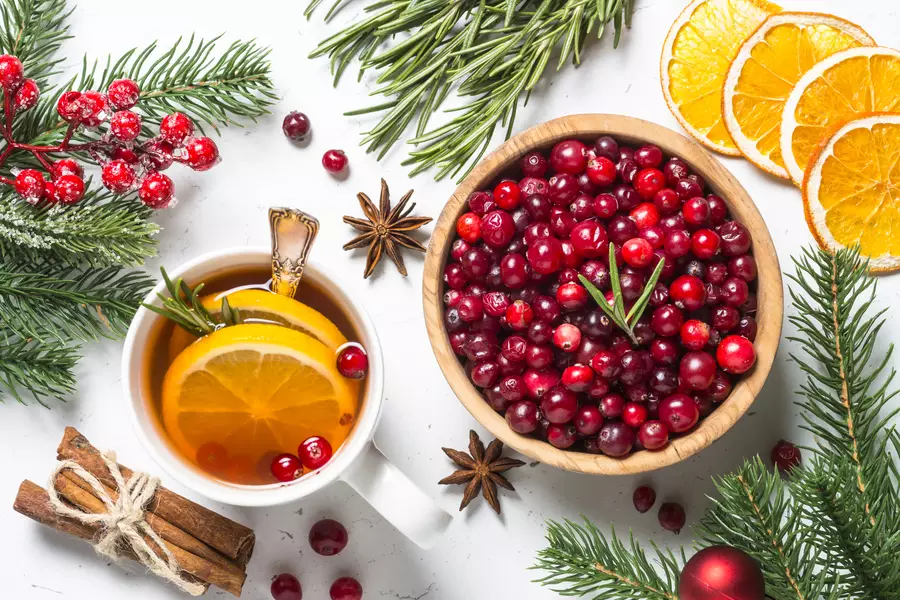 Uma mesa branca com laranjas cortadas em rodelas, frutas vermelhas e folhas verdes