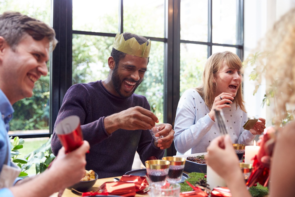 grupo de amigo sentados ao redor de uma mesa, brincando e dividindo comida