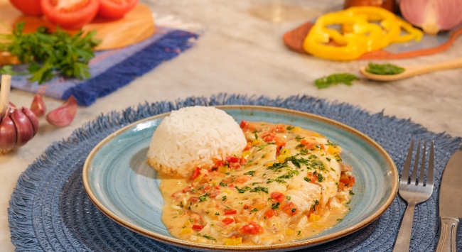 moqueca de peixe e arroz branco servido em um prato redondo 