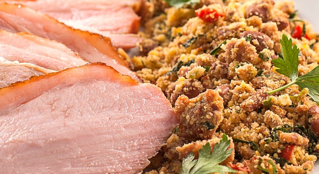 Pernil suíno fatiado servido com feijão tropeiro.