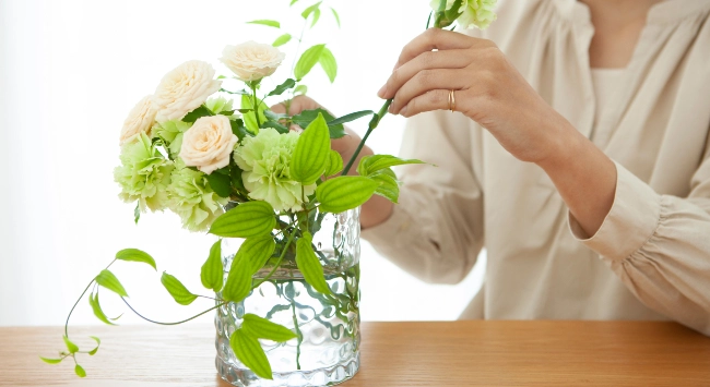 Uma pessoa fazendo um arranjo de flor delicado e lindo.