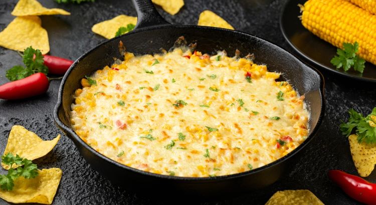 Creme de milho gratinado está servidos em frigideira preta.