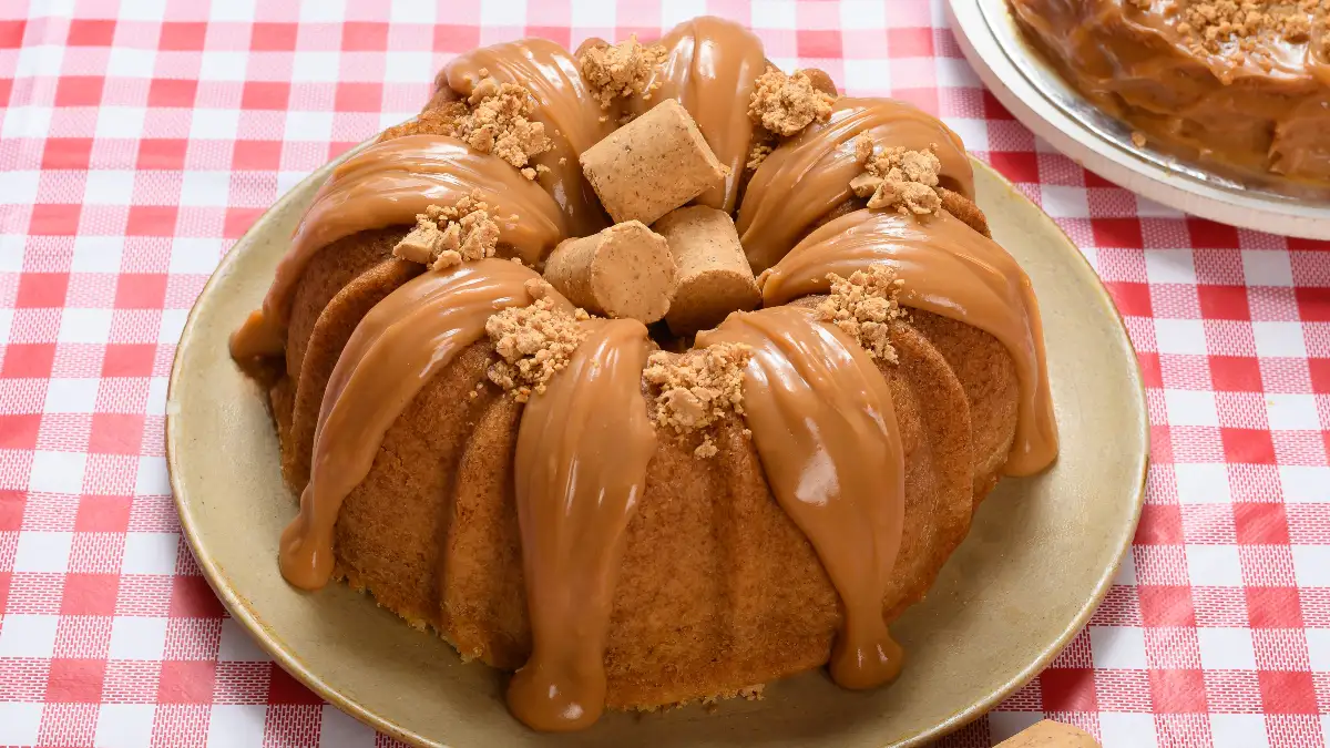 Bolo de paçoca servido com cobertua e duas paçocas em cima.