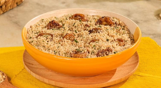 Farofa de banana servida em tigela amarela e bege.
