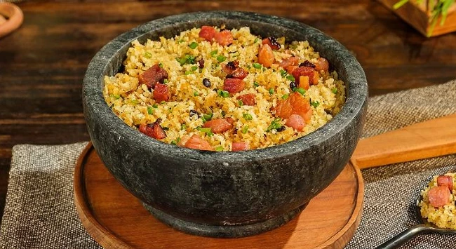 farofa de maracujá com bacon em tigela escura em uma mesa de madeira.