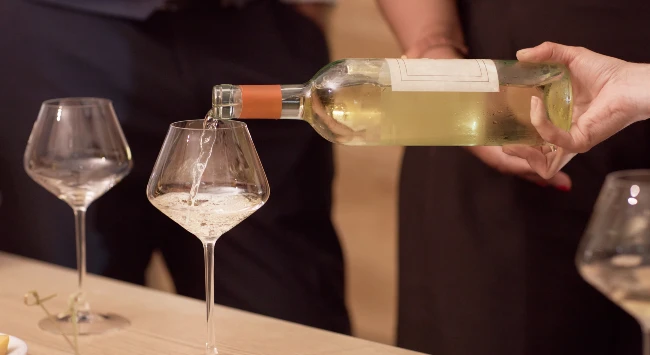 Vinho branco sendo servido em duas taças de vidro.